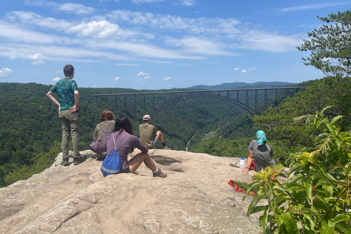 Campers resting on a rock overlook above the New River Gorge