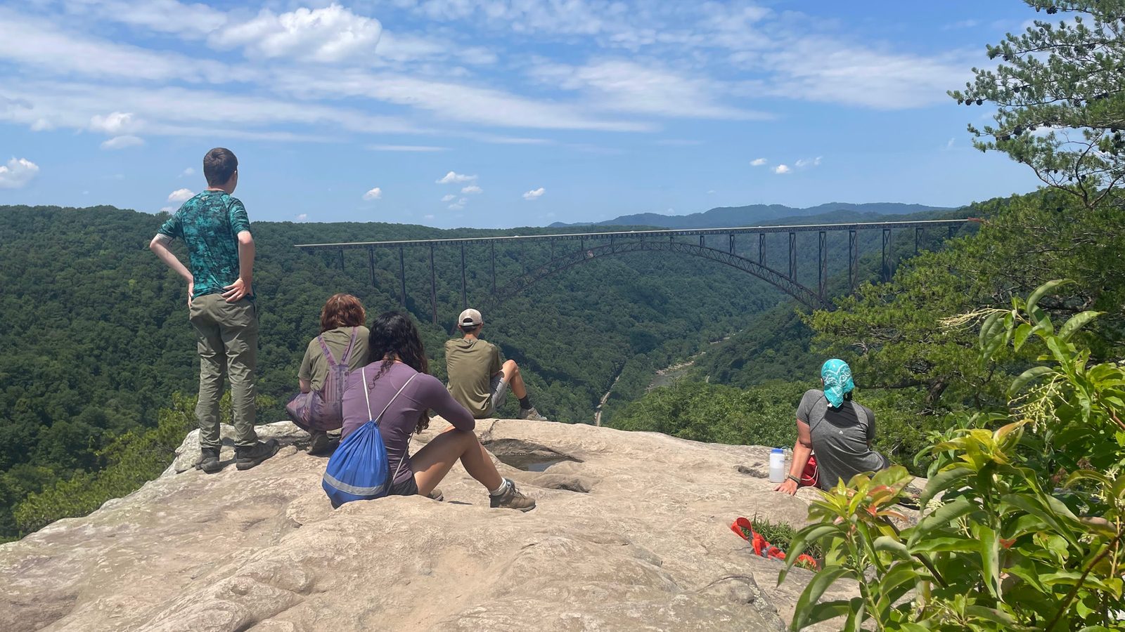 Campers resting on a rock overlook above the New River Gorge