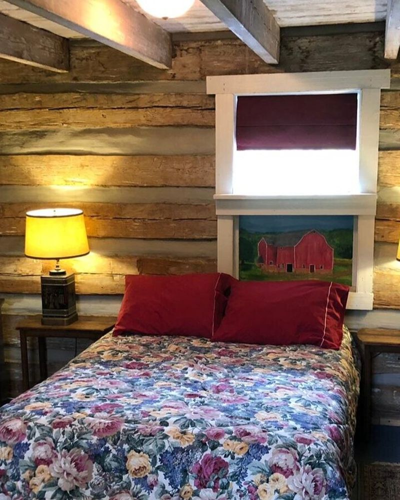 A bed beside a window in a rustic log-walled lodge room