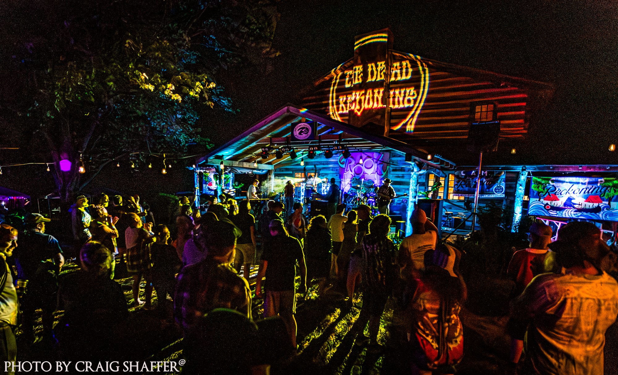 Fans filling the lawn at night in front of the colorfully lit Camp Reckoning stage