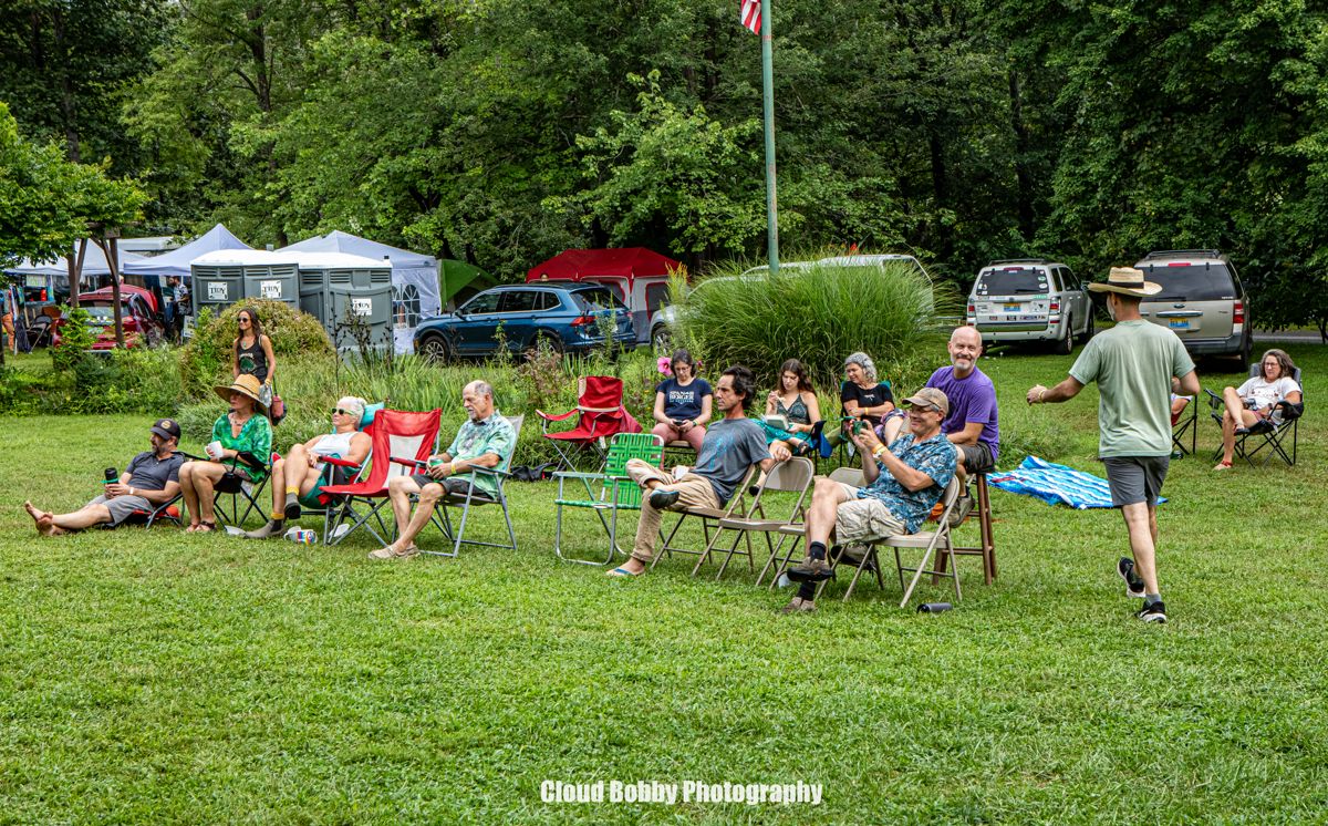 Festival guests relaxing in chairs on the lawn near their tents