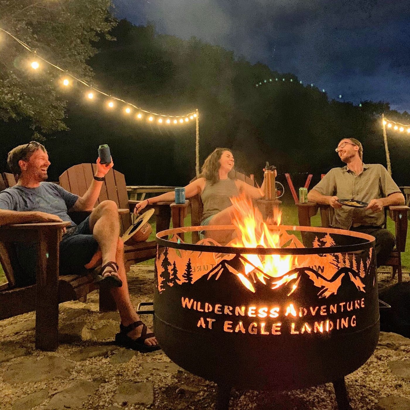Guests gathered around an outdoor fire pit under string lights