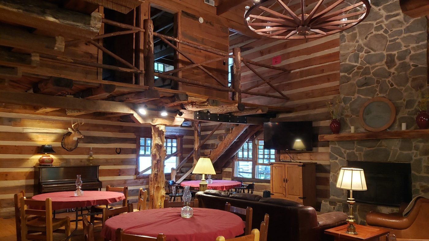 Stone fireplace, wooden balcony and tables in the Main Lodge