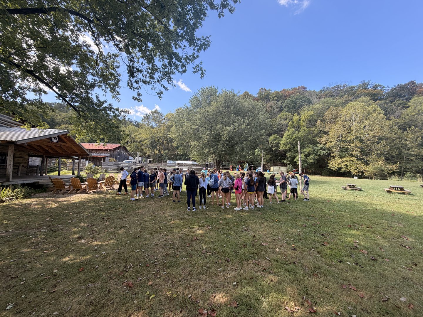 Students gathered on the lawn between the lodge and wooded hills