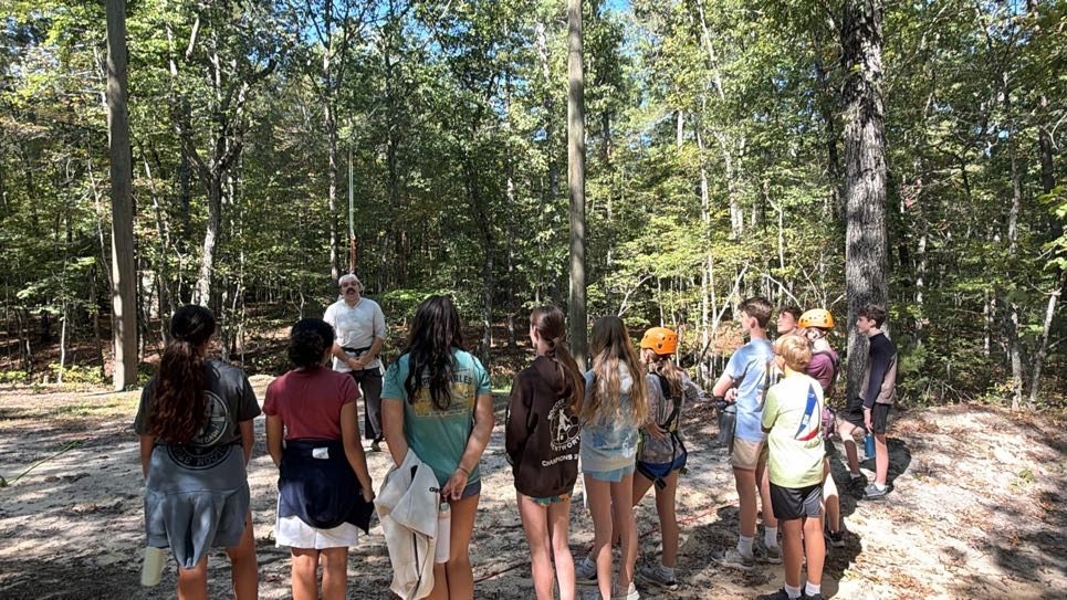 Students gathered around an instructor in the woods
