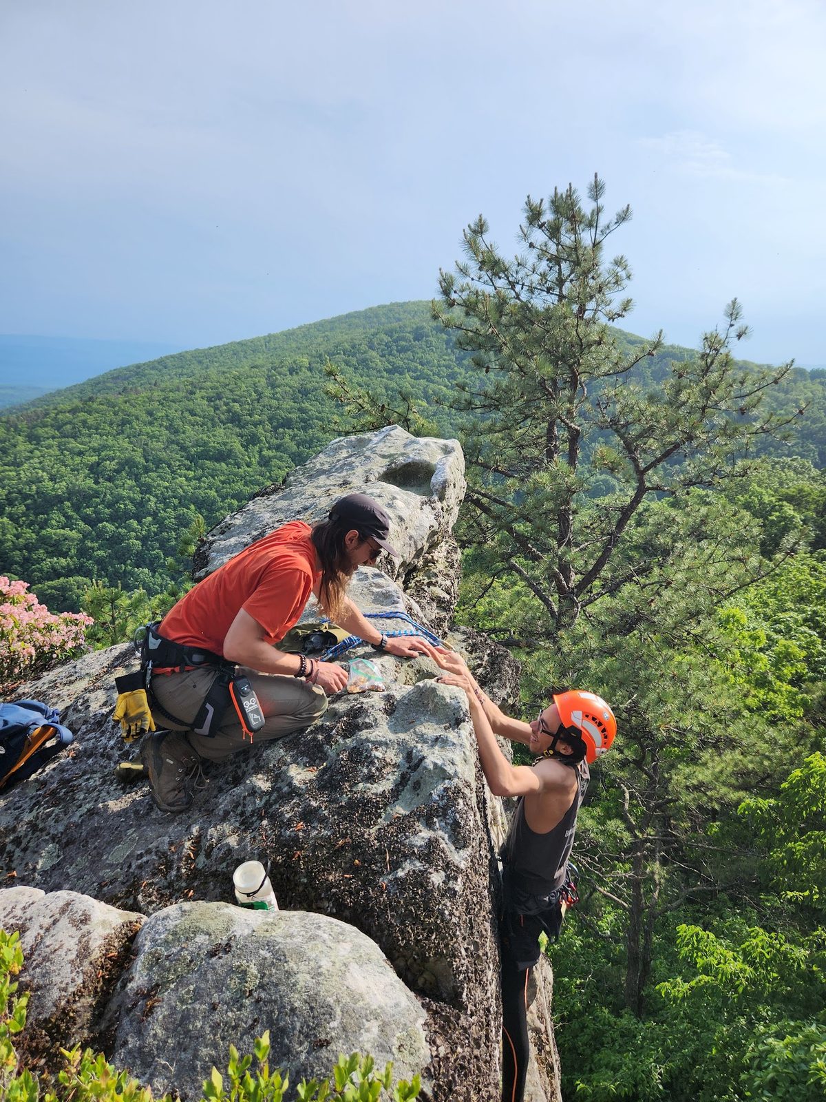 A climbing instructor helping a climber up a rock face