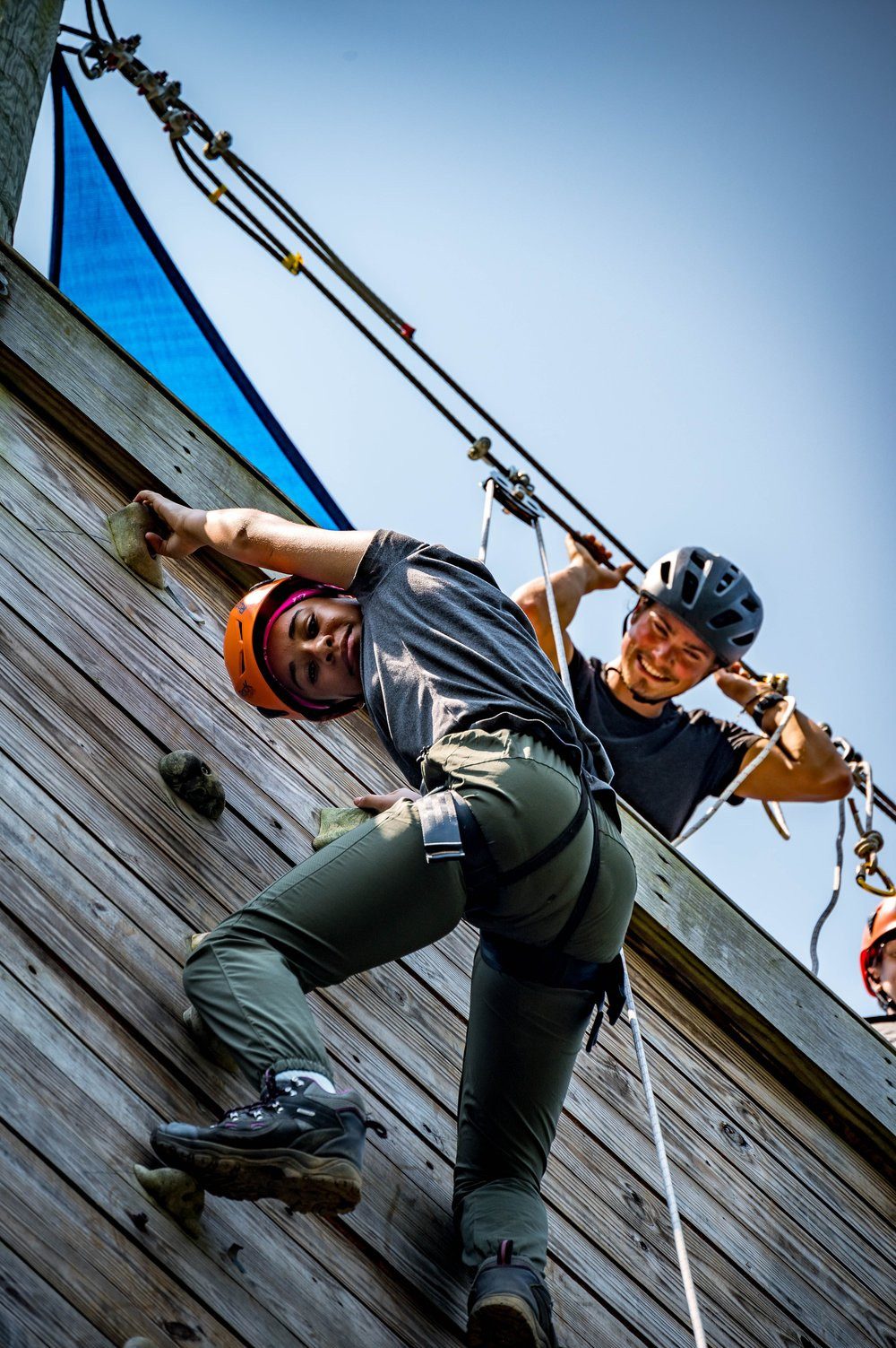 A camper climbing the wooden climbing wall