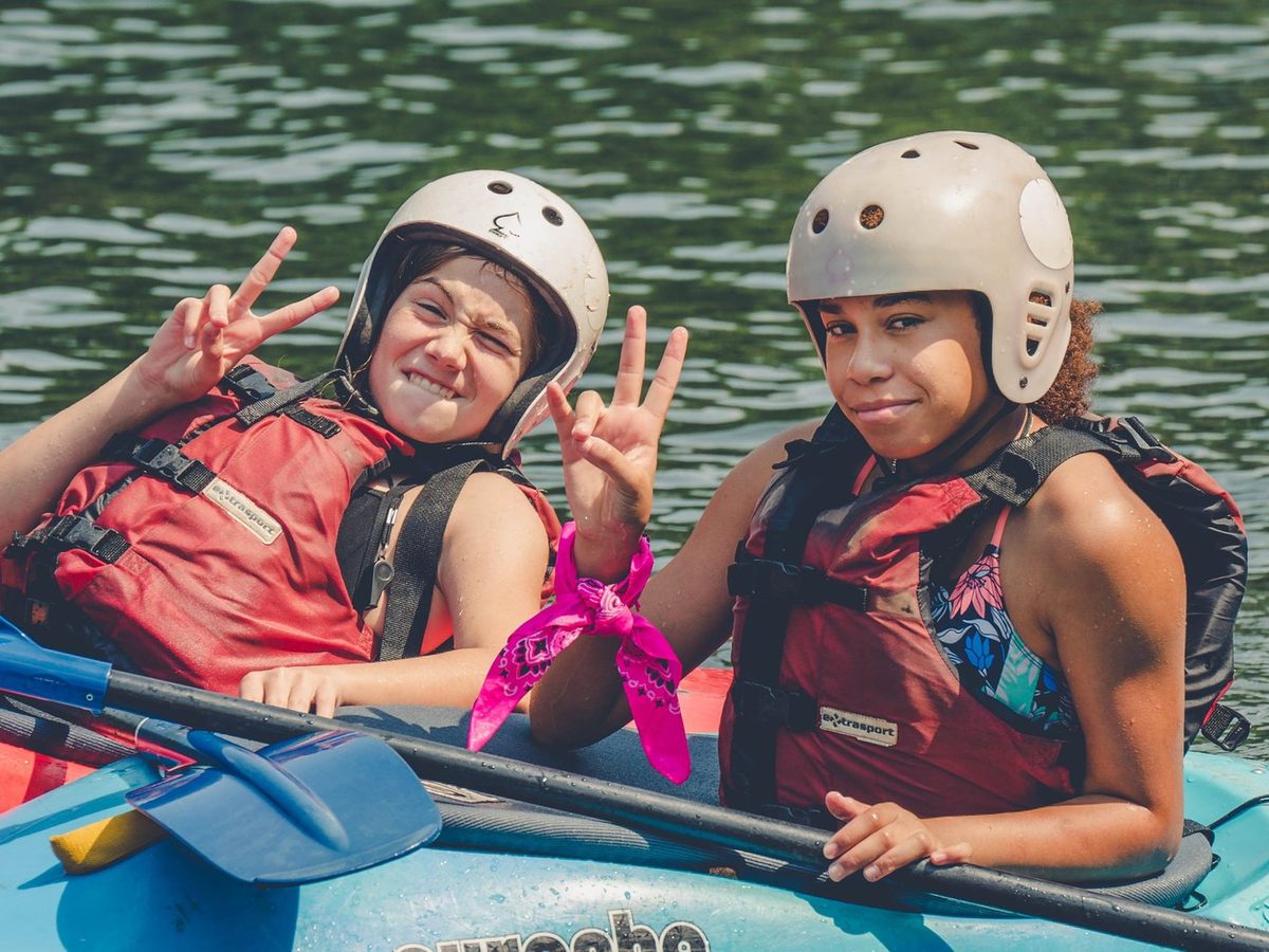 Two smiling WAEL campers in helmets and life jackets with their kayaks