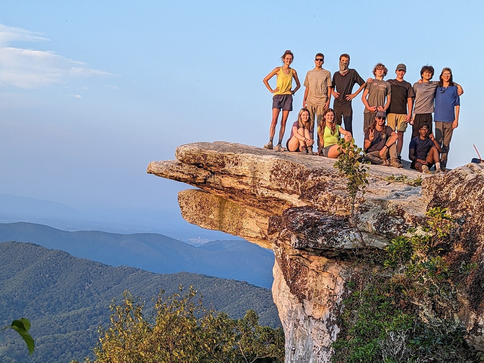 A group of young adults standing on a rock ledge high above the Blue Ridge Mountains