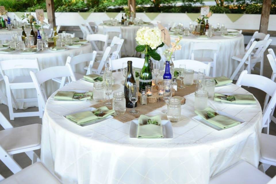 Round tables with white linens and green place settings in the pavilion