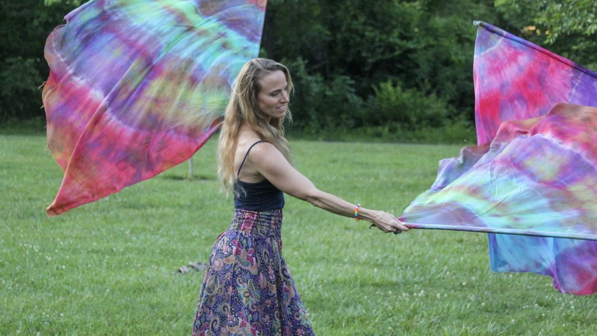 A participant moving silk flags on the lawn at Yoga Venture