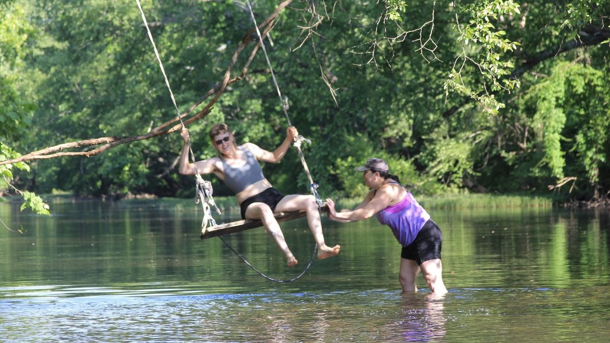 Guests enjoying a rope swing over the creek at Yoga Venture
